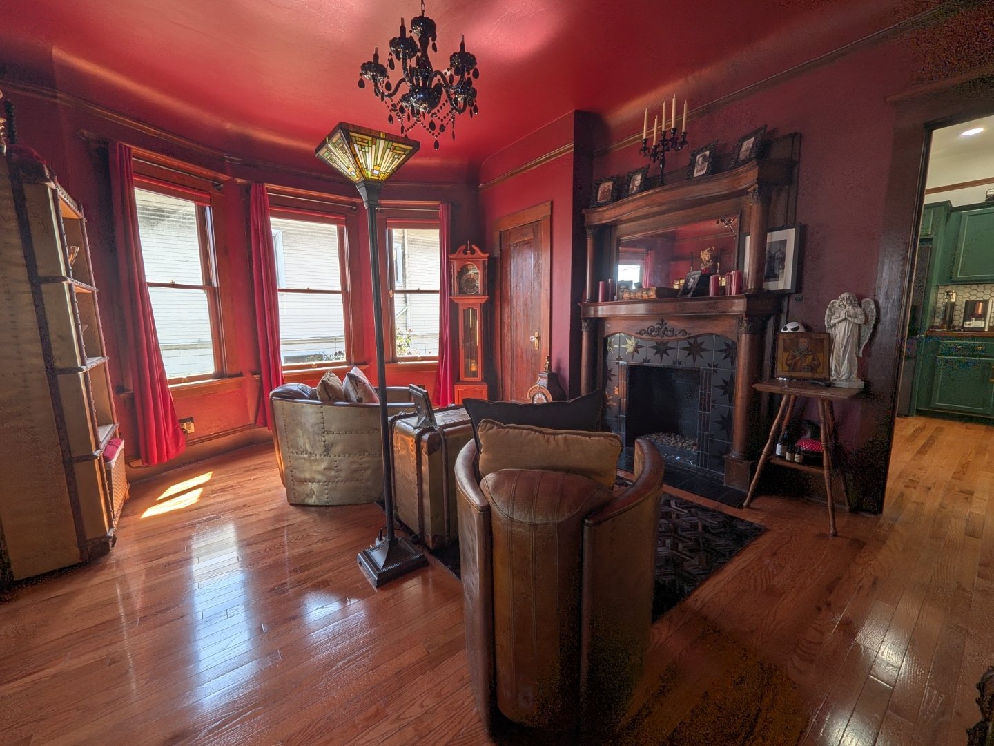 Burgundy parlor in the evening with fireplace and chandelier glowing